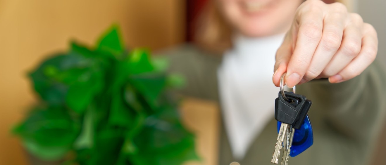 A person holding a plant and moving in after signing their first apartment lease.
