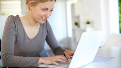 beautiful-young-woman-studying-at-home-on-laptop