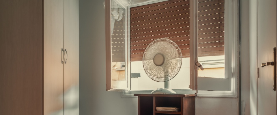 A person using a fan to cool down an apartment.