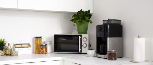 A microwave and a modern coffee machine on a white countertop to illustrate how to save on utility bills.