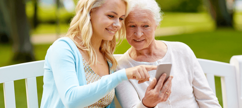 woman helping older woman use resident portal on smartphone