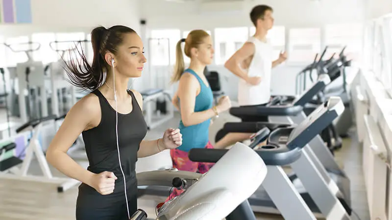 people exercising in fitness center, a popular amenity in apartment complexes