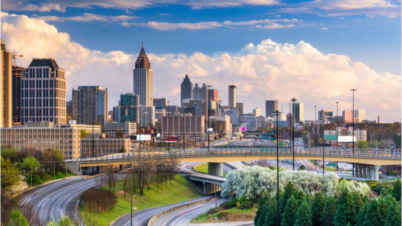 A shot of the Atlanta skyline at sunrise, with empty roads and green spaces.