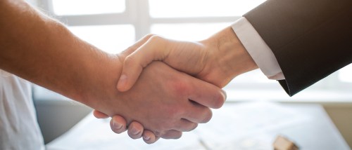 Two people shaking hands after creating a roommate agreement.