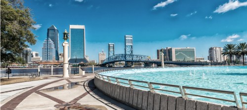 A shot of city buildings near a large, man-made fountain on a sunny day in Jacksonville, FL.