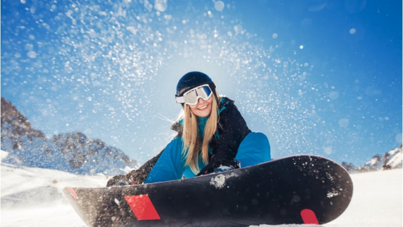 girl sitting by her snowboard