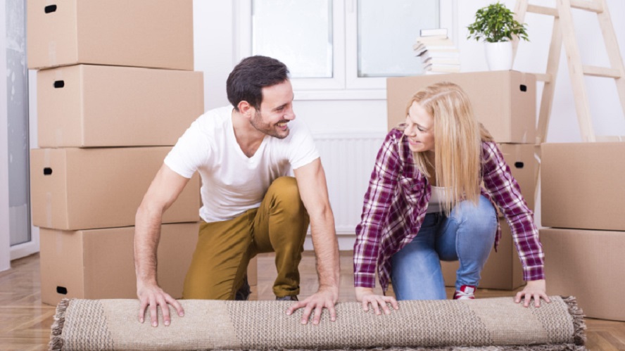Young Couple Moving and Rolling a Carpet