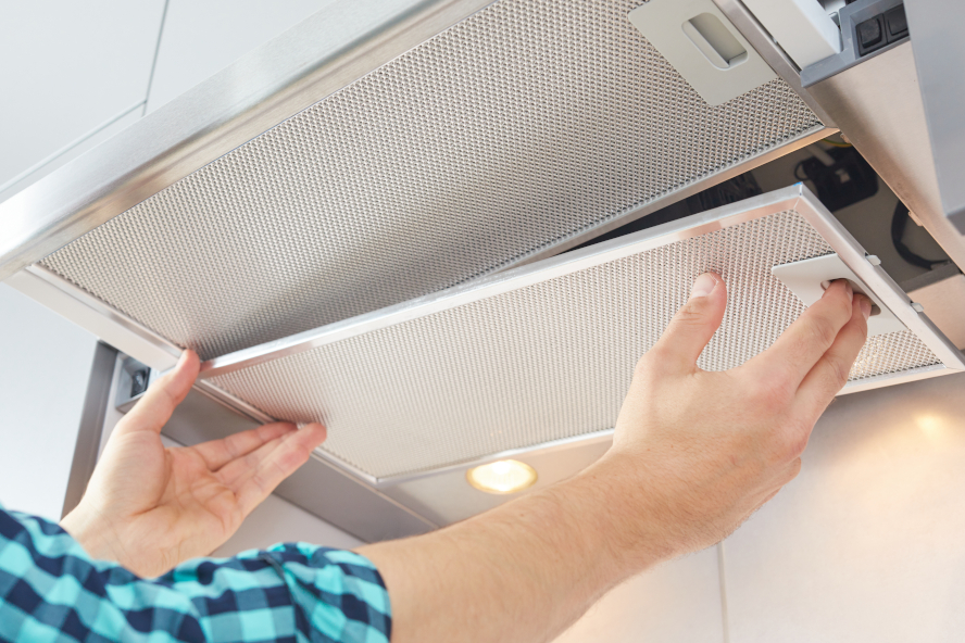 person in checkered shirt removing filter from cooker hood