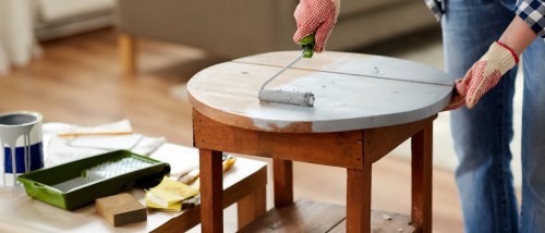 hands painting a diy wooden chair using a paint roller