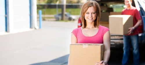 couple moving boxes in a storage unit from a truck