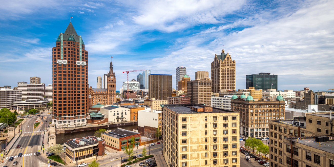 Downtown Milwaukee, WI, skyline featuring a mix of historic and modern buildings under a partly cloudy sky.