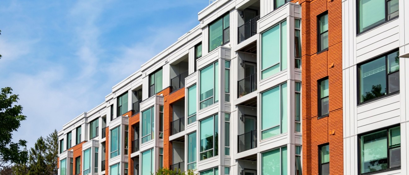 A modern apartment building with balconies and large windows.