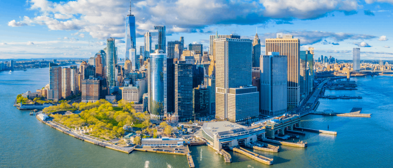 wide view of Manhattan's Financial District with many sky scrapers surrounded by water