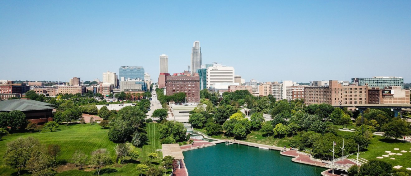 tall buildings in the background and a body of water and green tress in the front