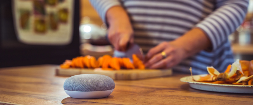 Woman oreoaring a meal assisted by a voice-controlled smart speaker.