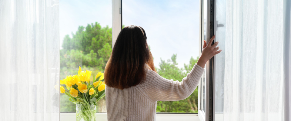 picture of woman opening the window to let air in 