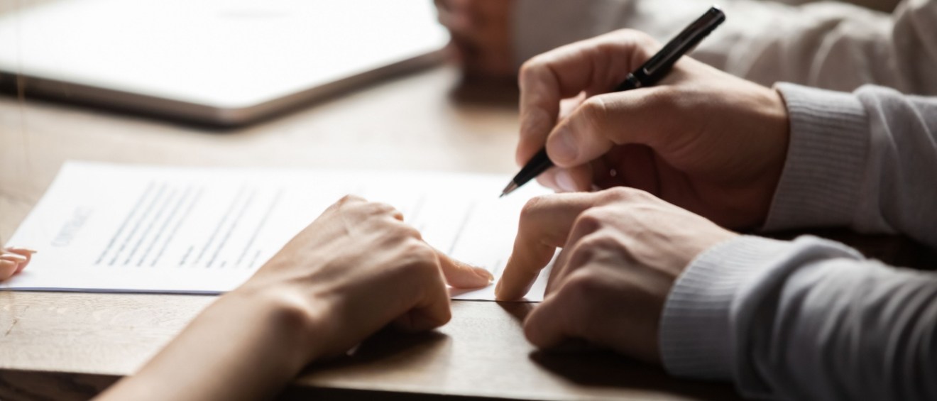 hands holding a pen and signing a standard lease agreement
