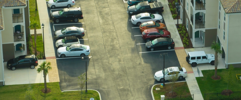 Aerial view of cars parked in a residential apartment lot, highlighting the space-saving benefits of tandem parking for renters in crowded urban housing communities.