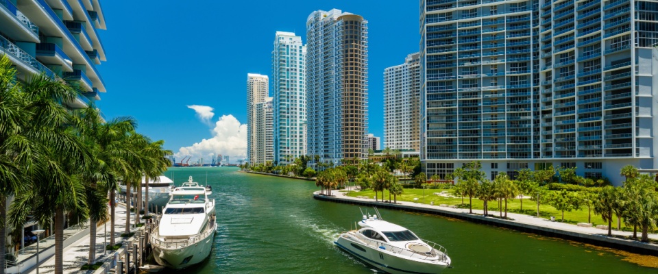 Boat cruising down the Miami River inlet in the downtown Brickell district with luxury apartment buildings along the river.