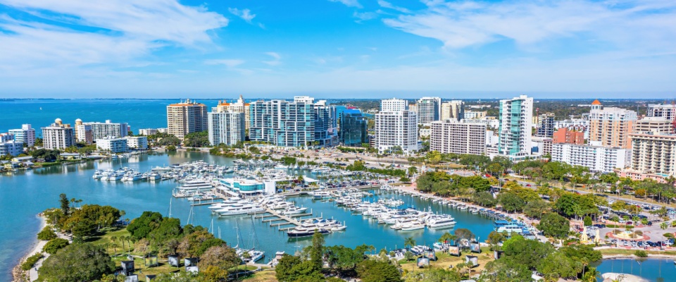 A view of the Downtown Bayfront Park in Sarasota, FL, with the iconic Marina Jacks and the Golden Gate bridge in the background.