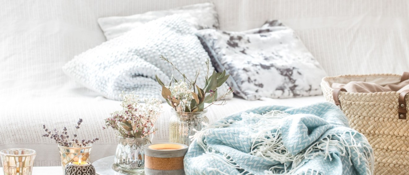a turquoise blanket and wicker basket with a vase of flowers and candles.