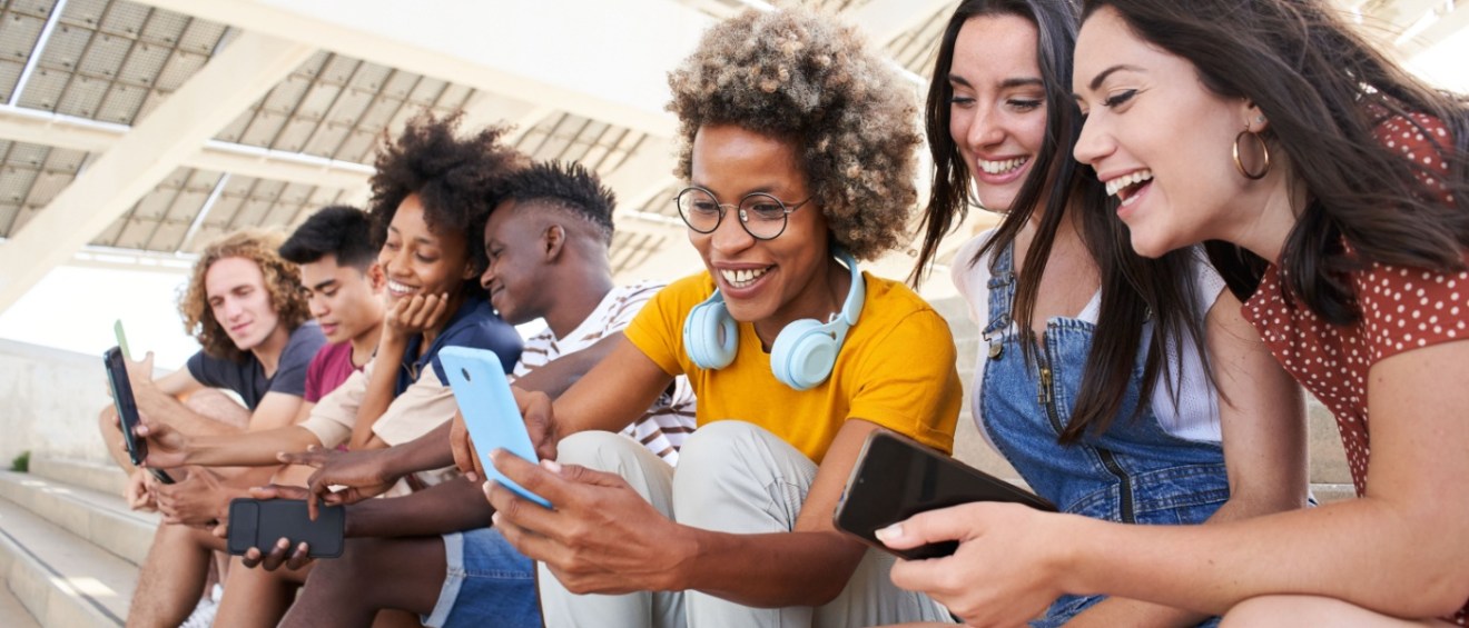 Group of young mixed race people with mobile phones. Excited students using their technological devices. Concept of young enterprising, friendly, selfie, app, hipster, millennial.