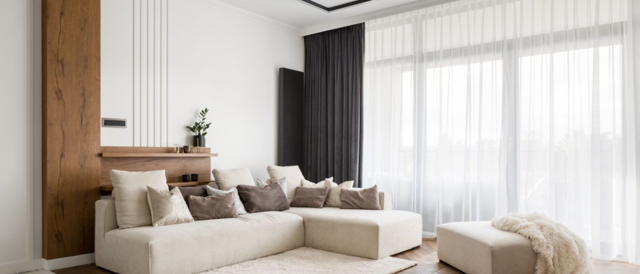 upscale apartment living room with large windows, wooden floors a large sofa with pillows and good quality furniture