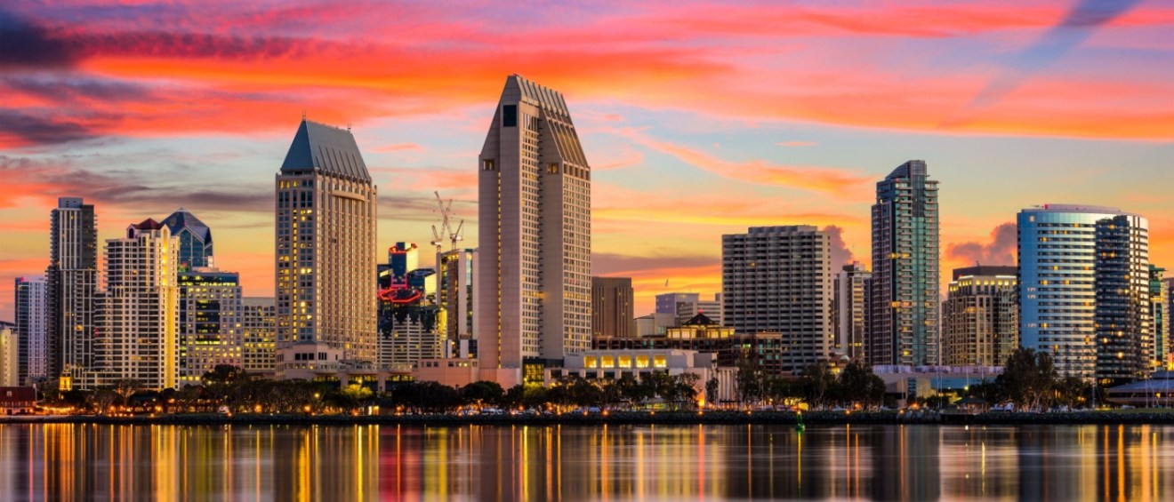 San Diego skyline at sunset with colorful sky and waterfront reflections.