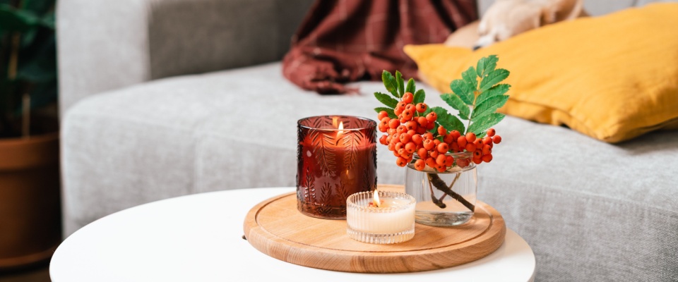 A table with aromatherapy candles and a vase of red berries.