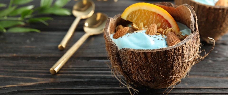 Coconut shell with spirulina smoothie on wooden table