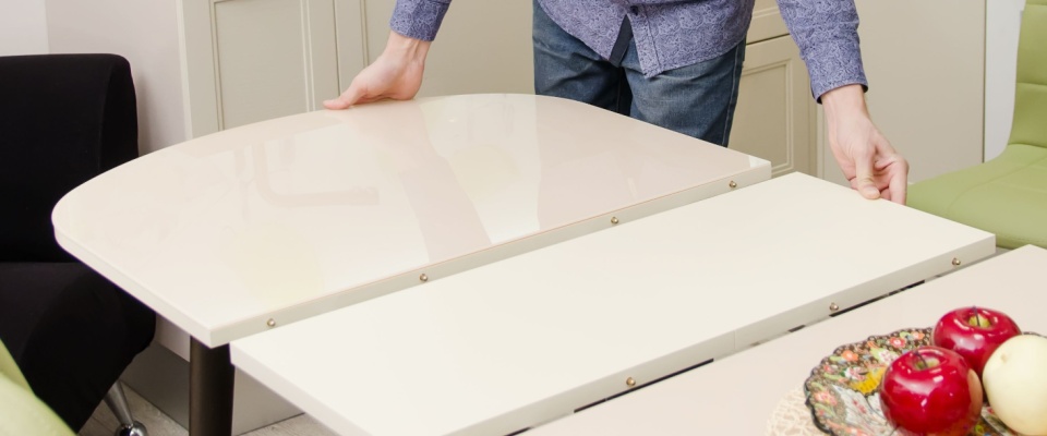 A person adjusting an extensible space-saving table in a kitchen.