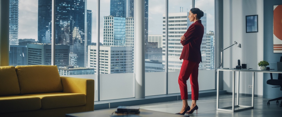 Woman looking out the window of a luxury apartment with a city skyline view.
