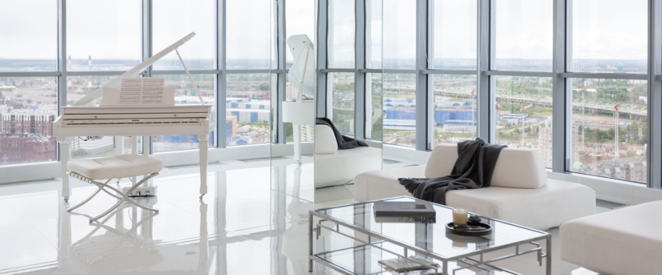 Bright, modern living room with white furniture and a grand piano in a luxury apartment.