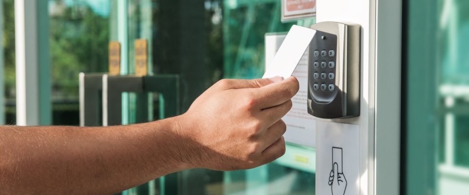 Hand using a key card on a secure entry system at a luxury apartment.