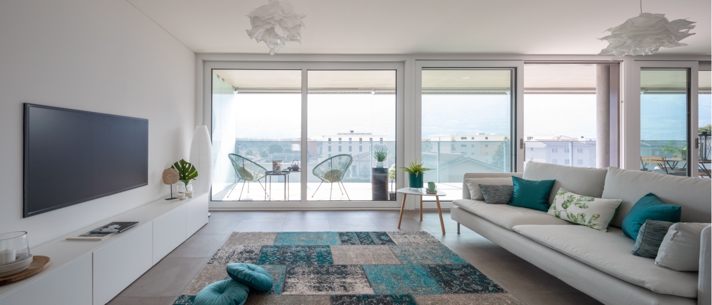 Modern, bright living room in a luxury apartment with large windows, stylish furniture, and a balcony view.