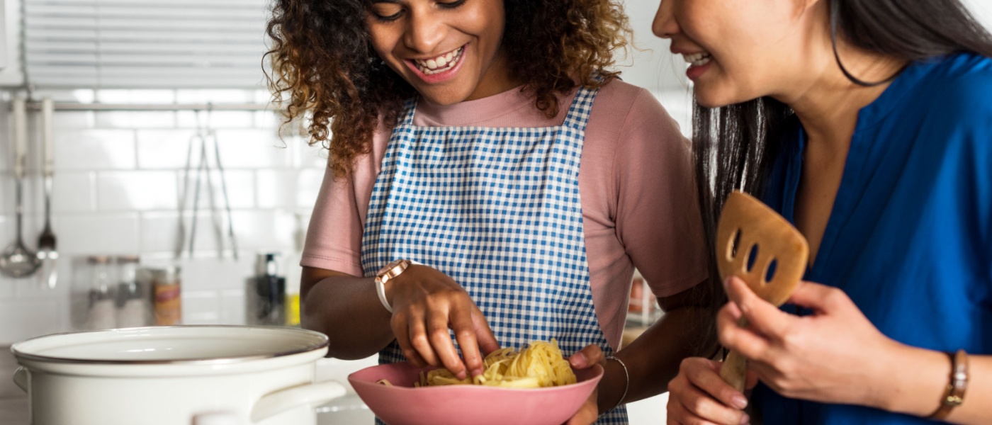 Roommates helping each other cook in a shared kitchen.
