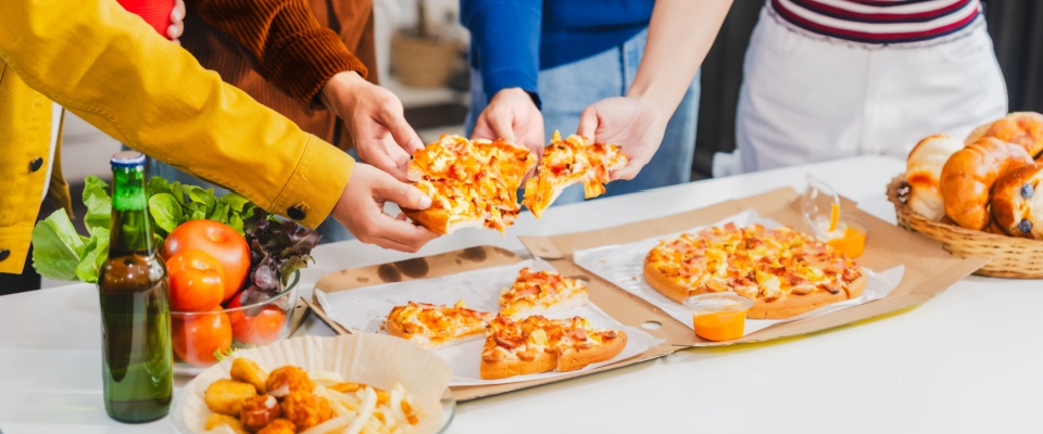Young students gather with friends for a pizza party, laughing and sharing slices.