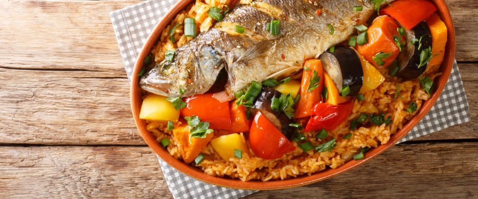 One-pot Thieboudienne Traditional West African Fish and Rice Dish with vegetables closeup in the dish on the table. 