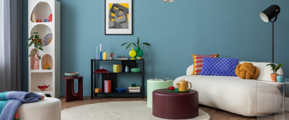 Modern and colorful interior of living room with design boucle sofa, mock up poster, shelf, plants, decorations and personal stuff.