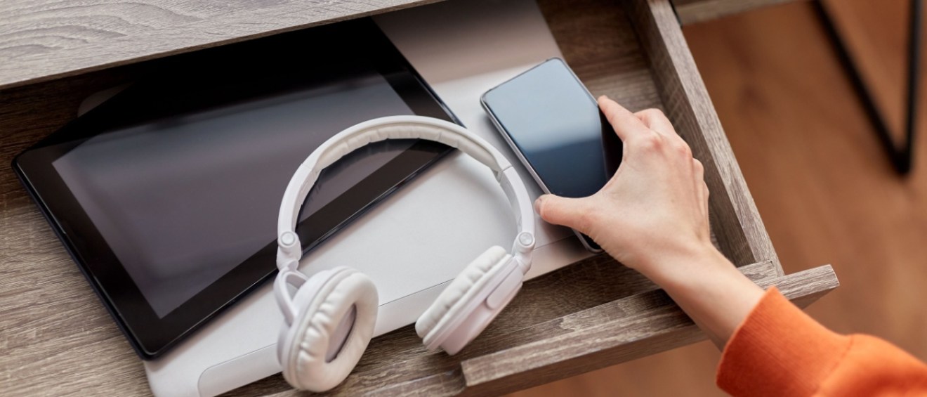 Smart home gadgets like phone, headphones and a tablet in an open drawer.