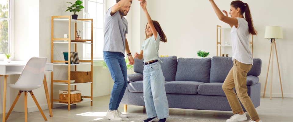 Young energetic mother, father and child having a party in a modern and spacious living room interior.