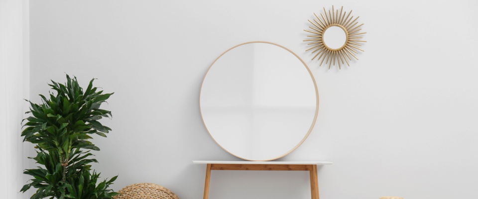 Stylish round mirror hanging on white wall in room.
