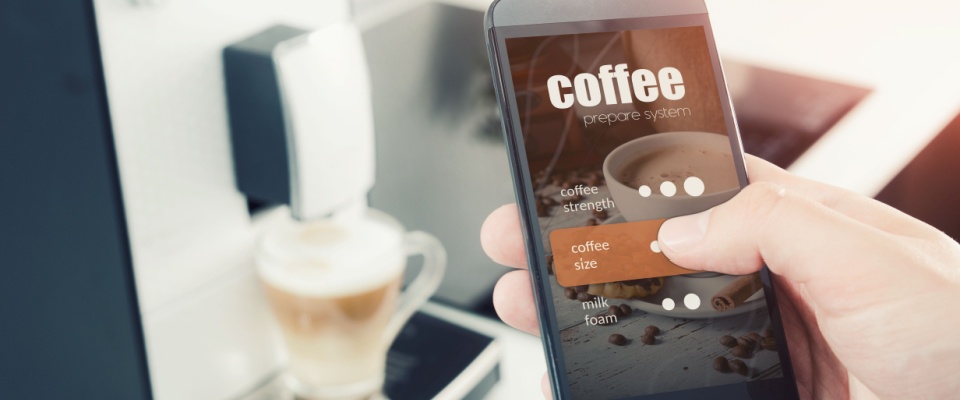 A person is using a smartphone app to control a smart coffee maker, selecting coffee size and strength settings