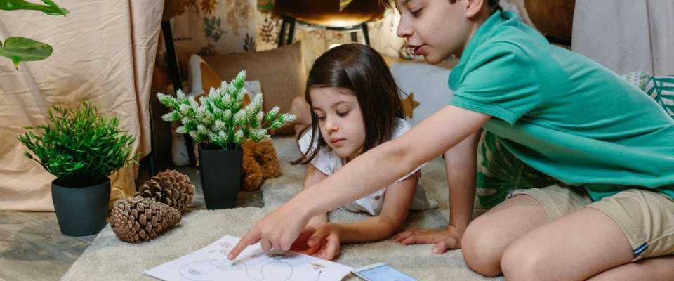 Children playing treasure hunting game in a DIY tent at home.