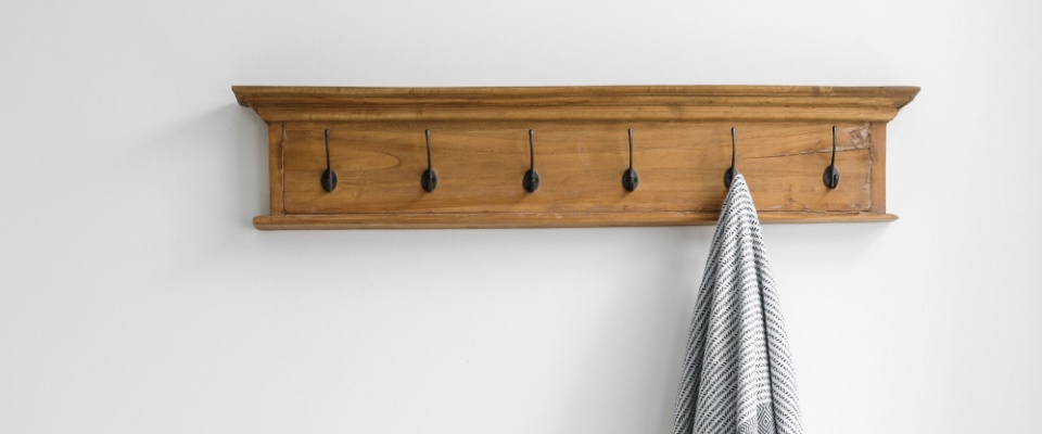 Vertical shot of stylish vintage wall hooks in entryway, home decorations and plaid clothes.