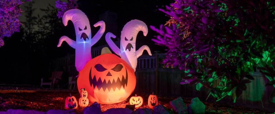 A set of inflatable Halloween decorations, colorfully lit up during the nighttime.