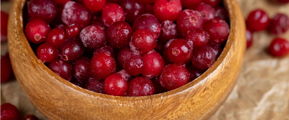 Frozen ripe cranberries scattered on the table, showcasing a sweet and sour, freshly harvested batch of quick-frozen berries.