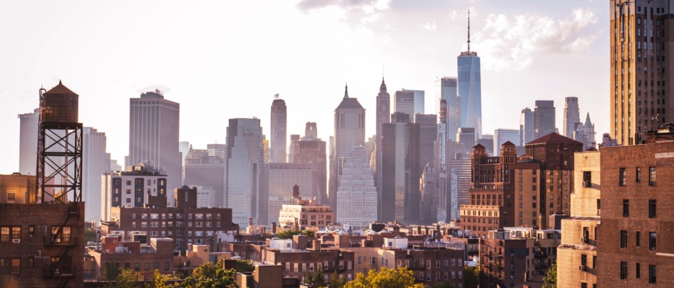 View of financial district Manhattan skyline and Brooklyn buildings at sunset.