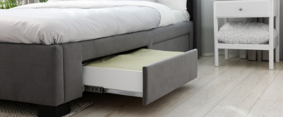 A storage drawer neatly filled with bedding, conveniently tucked under a comfortable bed in a cozy room.