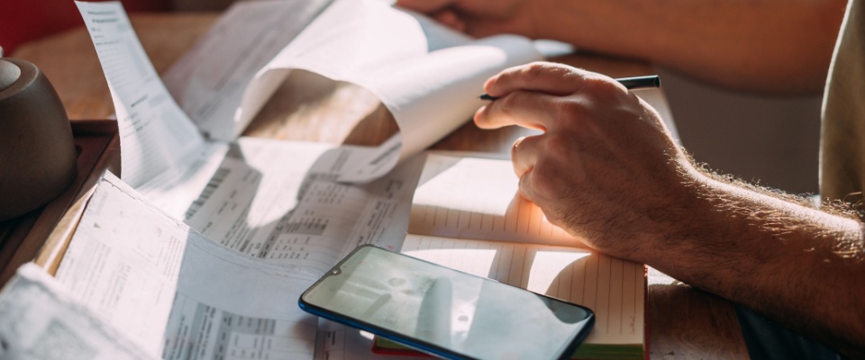 Close-up of men's hands with a calculator and utility bills.
